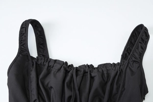 Close-up of black sleeveless dress with ruffled shoulder straps and ruched neckline detail