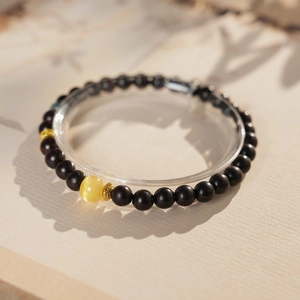 Detailed view of sandalwood beads bracelet with cat-eye amber charm in natural sunlight