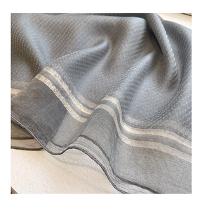 Detail view of grey silk-wool blend scarf showing fabric texture and silver metallic edges
