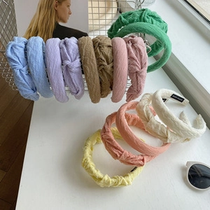 Close-up of pleated fabric knotted headbands in various colors on white mesh basket
