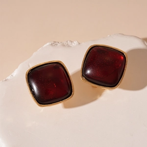 Macro shot of retro square resin earrings with gold edges on white stone display
