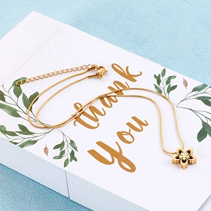 Detailed view of golden snowflake necklace on a Thank You gift box with snake chain detail
