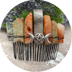 Natural crystal sunstone hair comb with silver triple moon symbol on mossy rock