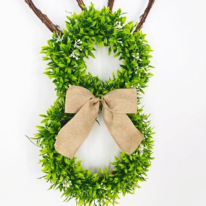 Detail of Easter bunny wreath with green leaves, burlap bow and natural rattan ears