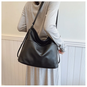 Detail of black pebbled leather tote bag showing side pocket and adjustable shoulder strap