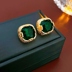 Dettaglio macro di orecchini vintage con zircone verde su custodia in pelle nera