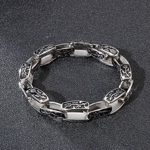 Detailed close-up of retro silver stainless steel bracelet links with floral engravings