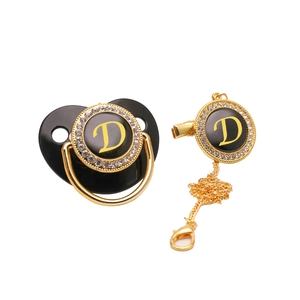 Detail of black baby pacifier and clip set with gold letter D and sparkling rhinestones