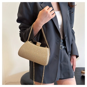Detail of glitter gold evening clutch bag with diamond-encrusted clasp and metal chain