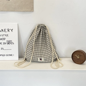 Close-up of black and white checkered canvas drawstring backpack with small logo detail