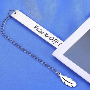 Detail of stainless steel bookmark with Fxxk Off text and feather charm on blue fabric
