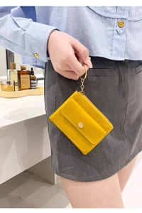 Detail showing hand holding yellow PU leather key pouch with metal ring and chain