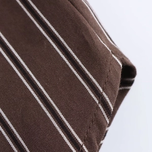 Macro view of brown striped woven fabric texture and precise stitching on the sleeve