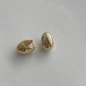 Close-up of gold oval hoop earrings with a polished finish on white background
