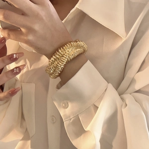 Detailed view of wide gold lava textured cuff bracelet styled on a model's wrist