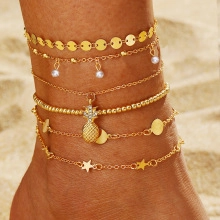 Close-up of golden multi-layer anklet set with butterfly and pearl on beach background