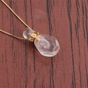 Detailed macro view of crystal perfume bottle pendant on a golden chain necklace