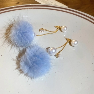 Detailed shot of blue faux fur pompom earrings with white pearl and 18K gold plated pins