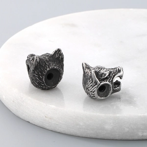 Detailed view of two wolf head stainless steel beads with aged texture for DIY jewelry
