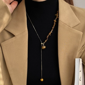 Detailed Y-shaped necklace with brown tiger eye stones and golden chain on a model