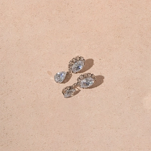 Détail macro de boucles d'oreilles goutte en argent avec zircons sur une surface en pierre