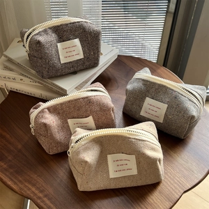 Detailed view of colorful herringbone tweed makeup bags with large white zippers