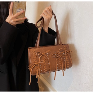 Close-up of brown PU leather shoulder bag featuring woven ropes and bow tassel details