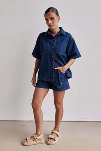 Detail eines dunkelblauen Denim-Sets bestehend aus Hemd mit Taschen und Shorts mit hoher Taille