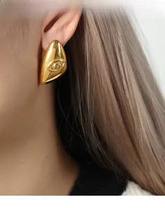 Detailed close-up of a gold-plated eye earring with diamond accent on model ear