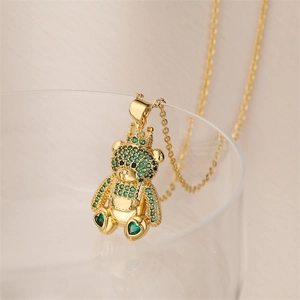 Detail of golden bear pendant necklace with crown and green crystals on glass rim