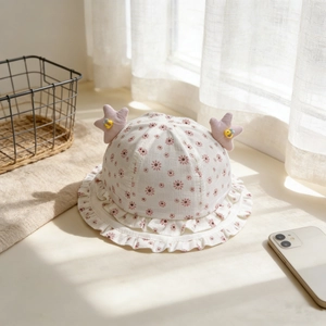 Détail du chapeau de soleil bébé avec fleurs roses, étoiles mauves et bord plissé