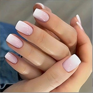 Detailed view of short square press-on nails with pink and white gradient glossy finish