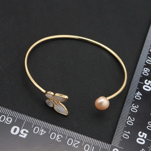 Golden butterfly bangle with pink natural pearl and zircon on a black background