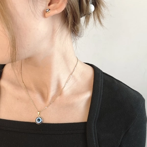 Close-up of elegant gold Evil Eye necklace and matching stud earrings worn by a model