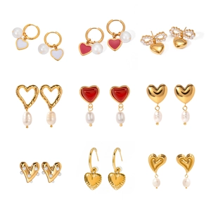 Collection of nine gold heart earrings featuring pearls and colored enamel on white background