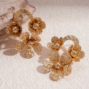 Gros plan de boucles d'oreilles fleurs dorées vintage avec pétales texturés et perles