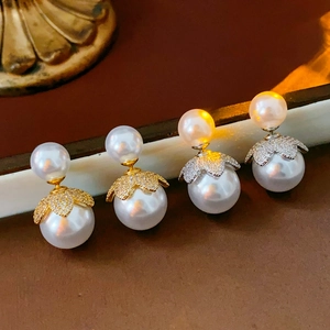 Makro-Detail von 18k gold- und silberplattierten Doppelperlenohrringen mit Zirkon-Blatt