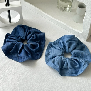 Macro view of blue denim fabric scrunchies with pleated texture and neat stitched edges