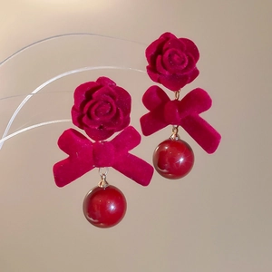 Détail des boucles d'oreilles rose et nœud floqués rouges avec perle brillante