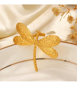 Close-up of golden dragonfly ring on a white porcelain plate with silk background