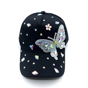 Close-up of sparkling rhinestone butterfly and floral accents on a black baseball cap