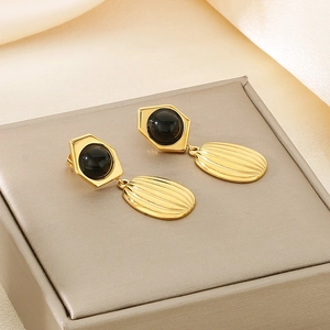 Elegant gold geometric earrings with black gems and textured oval pendants on display