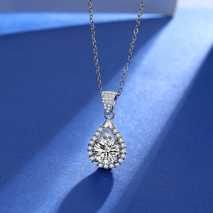 Macro shot of silver teardrop pendant with round moissanite in brilliant cut and pavé diamonds