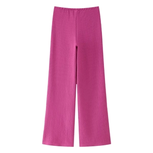 Dettaglio dei pantaloni a gamba larga rosa acceso a vita alta con tessuto a pieghe eleganti