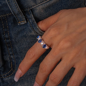 Detail of rose gold vintage ring with oval blue sapphires and zircon on denim background