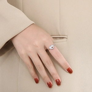 Macro detail of silver openwork heart ring with pavé micro-inlay on model's finger