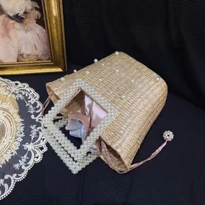Handmade woven straw basket bag with pearl accents, pearl handle and pink satin drawstring liner