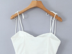 Detail of white camisole with delicate floral embroidery and slim shoulder straps