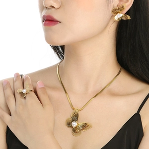 Detailed view of a gold butterfly jewelry set with pearls on a model neck and ears