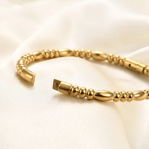 Macro shot of 18K gold-plated bamboo joint bangle with polished beads on silk fabric